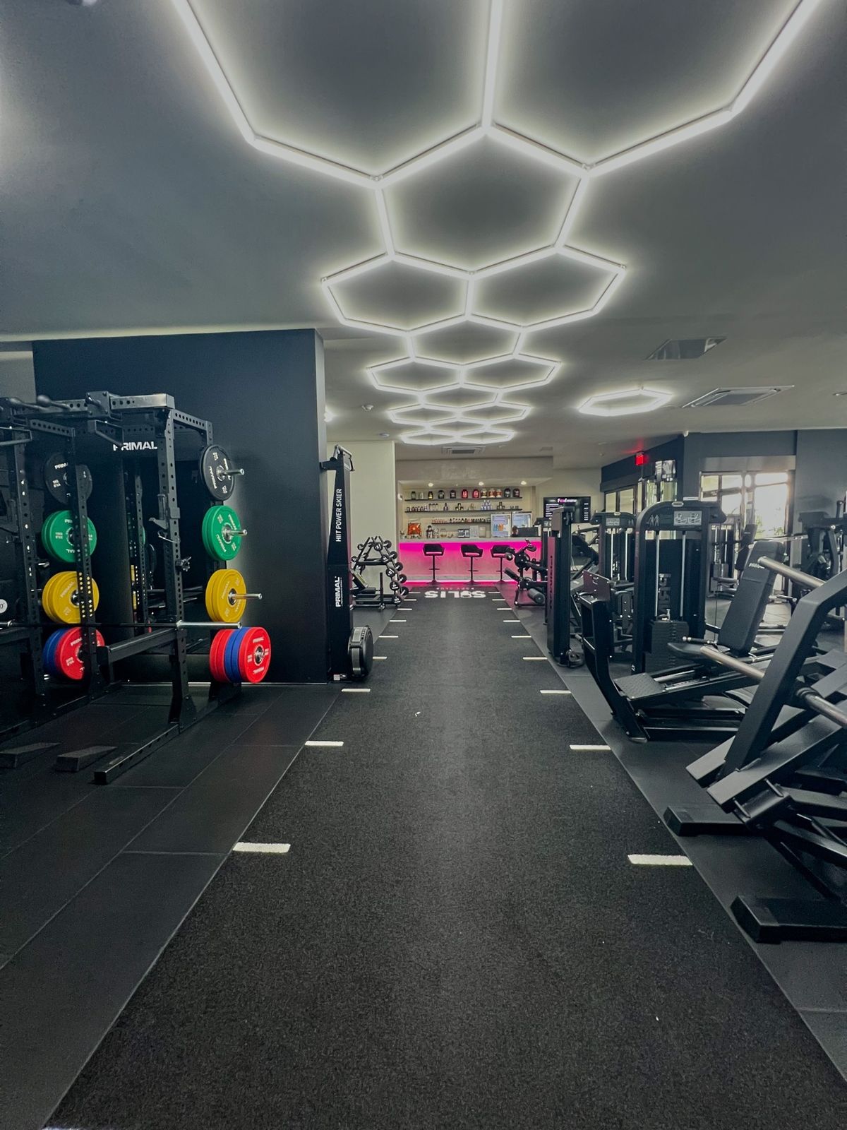 The machine floor at Solis Body Club under the hexagon lights, with Primal Strength plate-loaded machines
