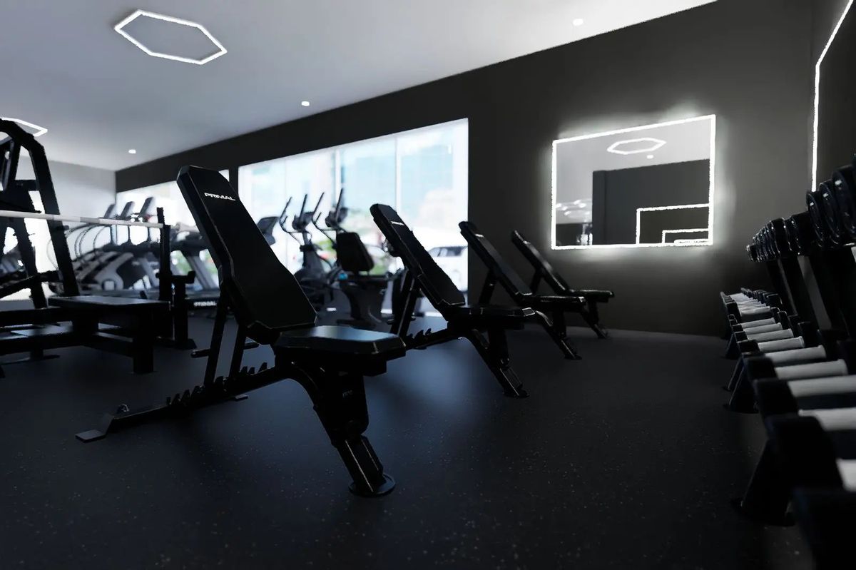 Primal adjustable benches and dumbbells, with cardio machines by the windows