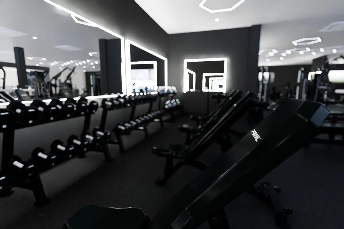Dumbbell racks and Primal adjustable benches in front of the lit mirrors