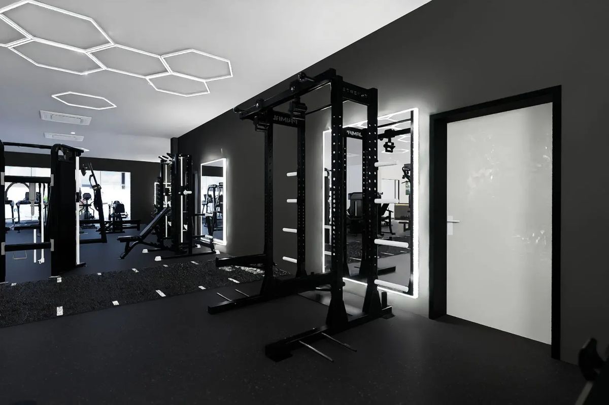 A Primal rack beside lit mirrors under the hexagon lights at Solis Body Club